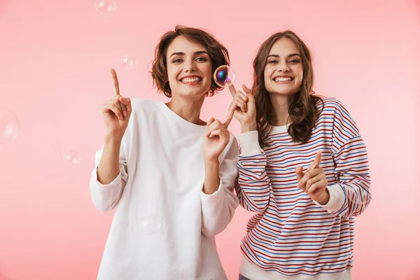 石鹸の泡でピンクの背景に分離されたポーズの幸せな若い女性の友人のイメージ — ストック写真
