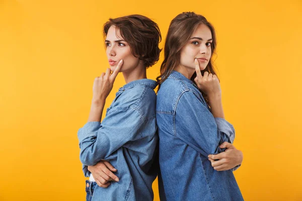 Imagem Sérias Pensativas Jovens Amigas Isoladas Sobre Fundo Parede Amarela — Fotografia de Stock