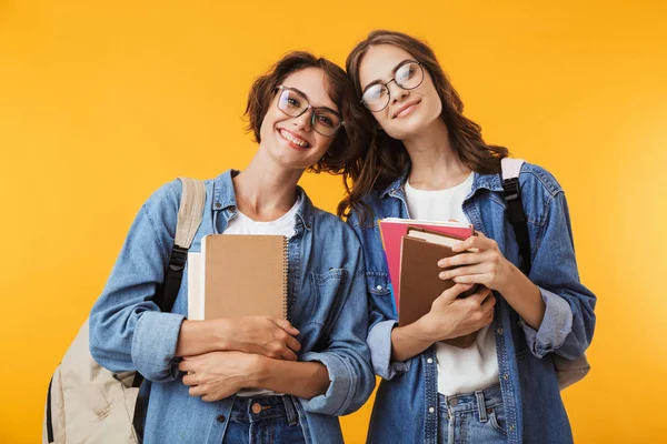 幸せな女性の友人が本を保持している黄色の壁の背景の上分離の陽気なイメージ — ストック写真