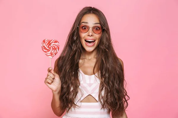 照片的开朗的女人20S 戴太阳眼镜笑和持有的棒糖查出粉红色背景 — 图库照片