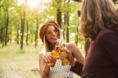 Mutlu çift hipsters adam ve gülüyor ve ormanda bira içmek kadın fotoğrafı