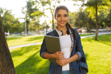 Mutlu genç güzel kadın öğrenci laptop kamera seyir tutan Park'ta yürüyordunuz görüntüsünü.