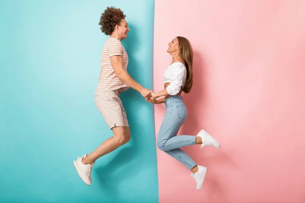 Renkli Arka Plan Atlama Ele Tutuşarak Mutlu Bir Genç Çift — Stok fotoğraf
