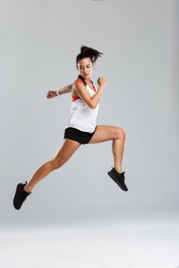 Atlama bir güçlü genç spor kadın görüntüsünü izole kapalı spor egzersizleri yapmak.