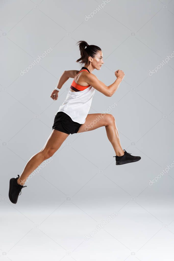 Image of a strong young sports woman jumping make sport exercises isolated indoors.