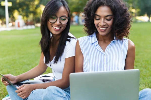 笑顔若い女の子留学キャンパスで草の上に座ってパソコンを持つ つのクローズ アップ — ストック写真