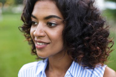 Mutlu gülümseyen genç Afrikalı kız açık havada parkta çim üzerinde görüntü.