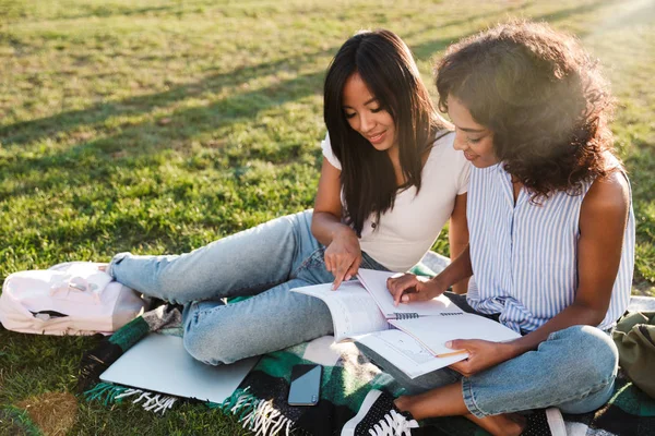 Dos Jóvenes Estudiantes Sonrientes Sentadas Una Hierba Campus Estudiando Con — Foto de Stock