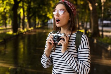 Heyecanlı şok genç güzel kadın açık havada yürüyüş fotoğraf makinesi ile görüntü.