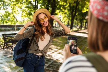 Cep telefonuyla fotoğrafını almak duygusal sevimli hanımlar arkadaşlar açık havada yürüyüş sırt çantaları ile fotoğraf.