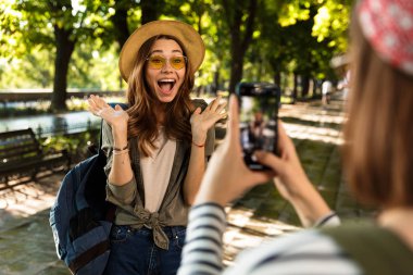 Cep telefonuyla fotoğrafını almak duygusal sevimli hanımlar arkadaşlar açık havada yürüyüş sırt çantaları ile fotoğraf.