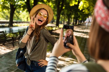 Cep telefonuyla fotoğrafını almak mutlu hanımlar arkadaşlar açık havada yürüyüş sırt çantaları ile fotoğraf.