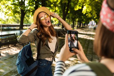 Cep telefonuyla fotoğrafını almak duygusal sevimli hanımlar arkadaşlar açık havada yürüyüş sırt çantaları ile fotoğraf.