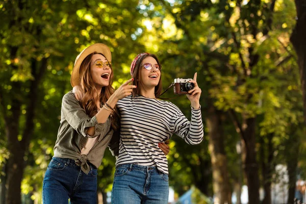 图像的兴奋漂亮的年轻快乐的妇女朋友走在户外与背包和相机指点 — 图库照片