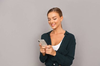 Neşeli mutlu iş genç kadının poz görüntü izole istimal hareket eden telefon gri duvar arka plan üzerinde.