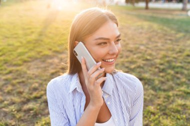 Cep telefonu açık havada üzerinde konuşan genç kız gülümseyerek yakın çekim
