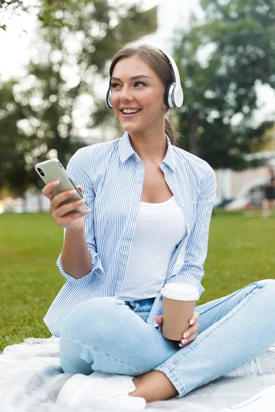 美丽的年轻漂亮的女人在公园户外听音乐使用手机的形象 — 图库照片