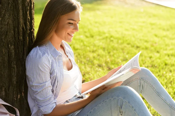 愉快的年轻女孩花时间在公园 坐在草地上的毯子 持有教科书 — 图库照片