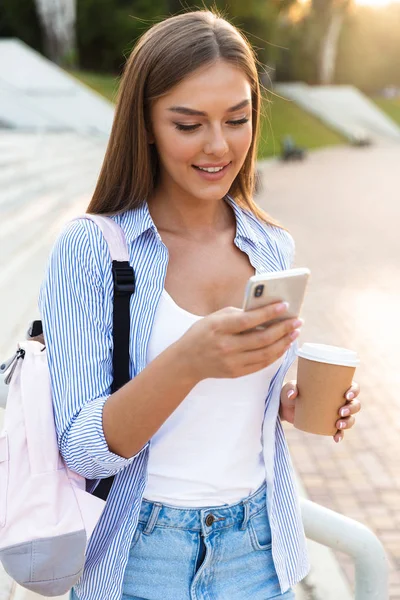 Sorrindo Menina Com Mochila Segurando Takeaway Café Usar Telefone Celular — Fotografia de Stock