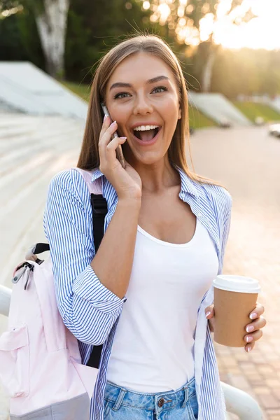 Sorrindo Menina Com Mochila Segurando Takeaway Café Enquanto Conversa Telefone — Fotografia de Stock