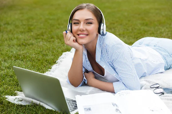 公園で過ごす時間 勉強して ラップトップ コンピューターに毛布を置くことのヘッドフォンで幸せな若い女の子 — ストック写真