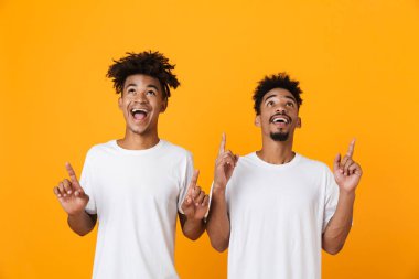 Sarı arka plan üzerinde izole ayakta t-shirt yukarı dönük iki mutlu erkek Afrika arkadaşlar