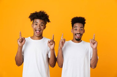 İki sarı arka plan üzerinde izole ayakta t-shirt yukarıyı erkek Afrika arkadaşlar heyecanlı