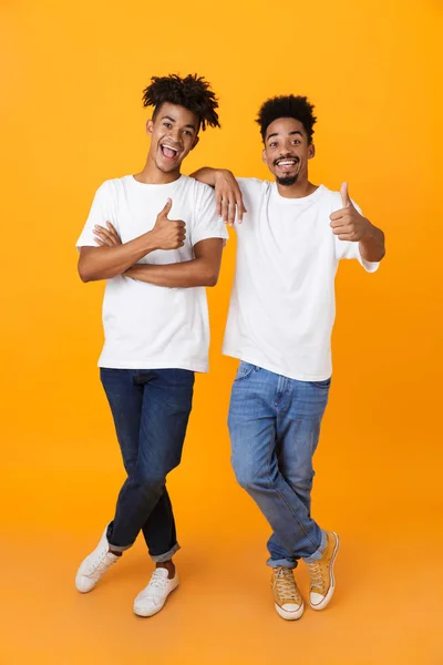 两个快乐的非洲男性朋友的全长在 T恤站在孤立的黄色背景 显示竖起大拇指 — 图库照片