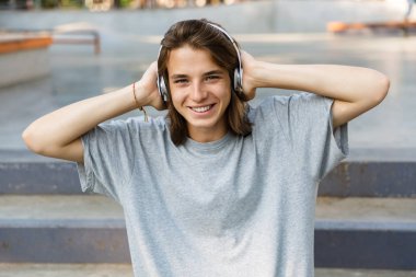 Kulaklık ile müzik dinlemek paten parkta vakit neşeli genç genç çocuğun yakın çekim