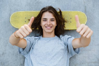 Bir sevimli genç teenge çocuğun paten parkta vakit, bir rampa adlı bir kaykay üzerinde döşeme, başparmak gösterilmesini üstten görünüm