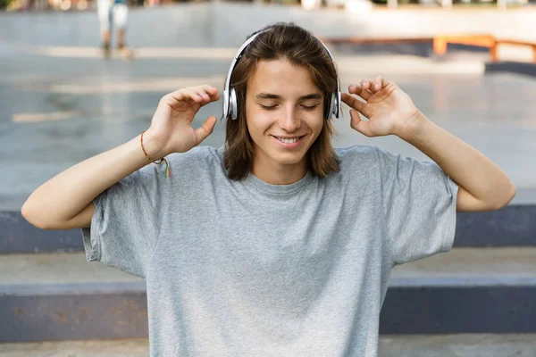 亲密的快乐的十几岁小男孩在滑板公园度过时光 用耳机听音乐 — 图库照片
