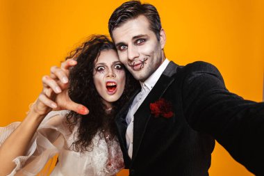 Komik güzel zombi gelin ve damat selfie kamera ve turuncu üzerinde izole gülümseyen yapma Cadılar Bayramı kostümleri