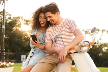 Genç çift erkek ve motosiklet üzerinde birlikte şehir sokak üzerinde otururken müzik kulaklık giyen kadın portresi