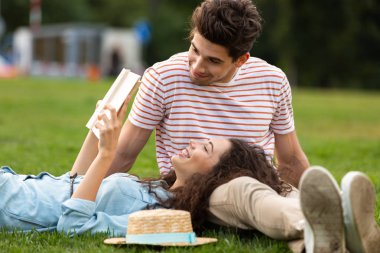 Görüntü çift erkek ve kadın 20'li yaşlarda park ve okuma kitabı yeşil çim üzerinde yalan