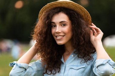 Görüntü arka plan bulanık ile yeşil parkta yürürken gülümseyen Avrupa kadın 20'li yaşlarda giyen hasır şapka