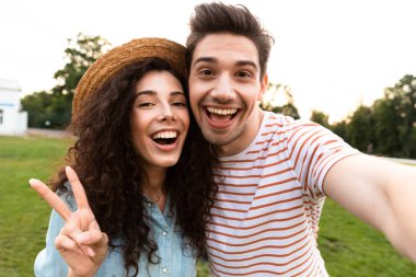 Görüntü genç çift erkek ve kadın 20'li yeşil park ve alma selfie cep telefonundan yürüyüş