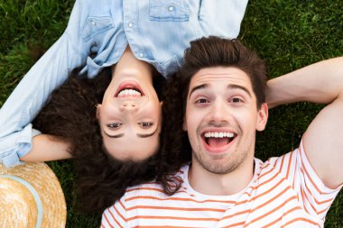 Görüntü neşeli çift erkek ve kadın 20'li yaşlarda üstten Park yeşil çimenlerin üzerinde ters kafa yanında yalan