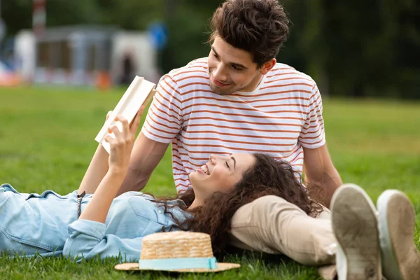 Görüntü çift erkek ve kadın 20'li yaşlarda park ve okuma kitabı yeşil çim üzerinde yalan