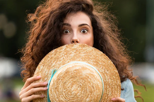 Görüntü arka plan bulanık ile yeşil parkta yürürken genç kadın 20'li yaşlarda holding hasır şapka