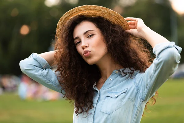 Görüntü arka plan bulanık ile yeşil parkta yürürken gülümseyen güzel kadın 20'li yaşlarda giyen hasır şapka