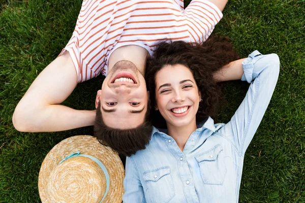 来自欧洲夫妇20岁的男女在公园绿草上与对面躺在一起的图片 — 图库照片