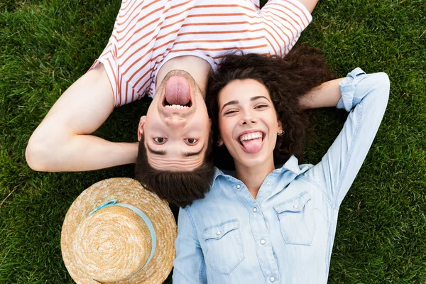 Görüntü üstünden eğlenceli iki adam ve kadın 20'li yaşlarda yalan Park yeşil çimenlerin üzerinde ters kafa yanında