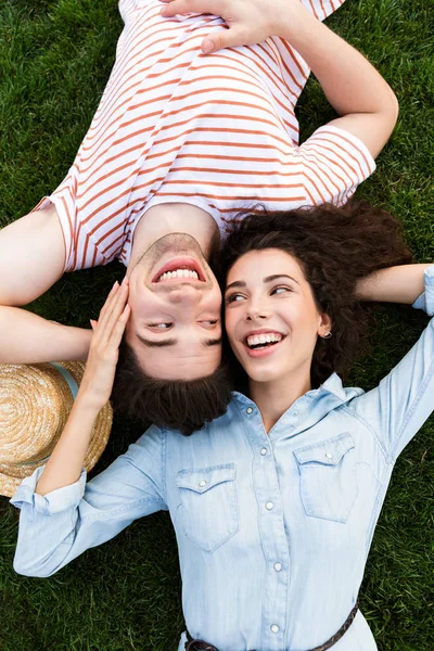 Görüntü üstünden sevgi dolu insanlar adam ve kadın 20'li yaşlarda yalan Park yeşil çimenlerin üzerinde ters kafa yanında