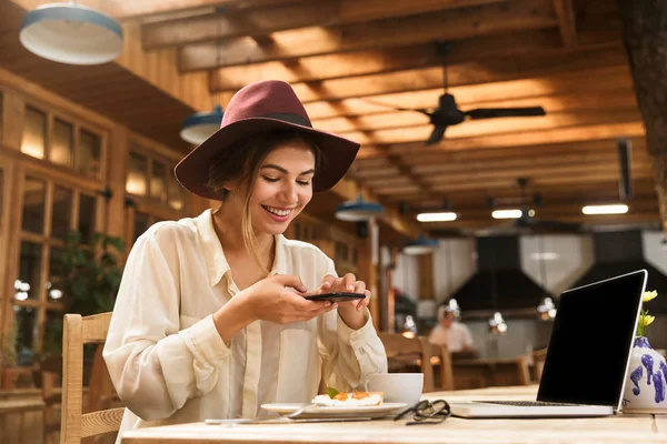 Retrato Mujer Satisfecha Usando Sombrero Fotografiando Comida Teléfono Celular Mientras —  Fotos de Stock