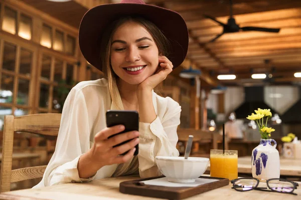Gyönyörű Visel Kalapot Használ Smartphone Elegáns Kávézójában Ülve Portréja — Stock Fotó