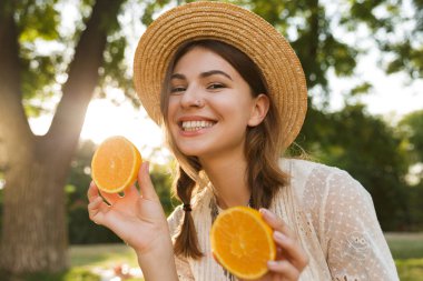 Turuncu dilimlenmiş vakit gösterilen Park, yaz şapkalı gülümseyen genç kızın yakın çekim