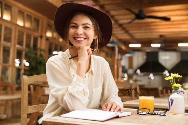 Menina Sorridente Chapéu Sentado Mesa Café Dentro Casa Fazendo Anotações — Fotografia de Stock