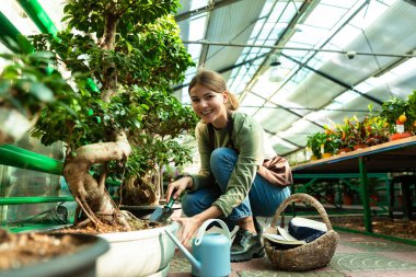 Görüntü güzel kadın bahçıvan 20'li yaşlarda giyen önlük sera ve bitki bakımı ile çalışma