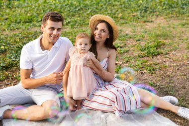 Genç aile piknik parkta, birlikte vakit küçük bebeği ile gülümseyen