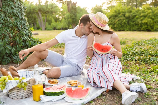 Birlikte iyi vakit, parkta piknik, öpüşme genç çift gülümseyen